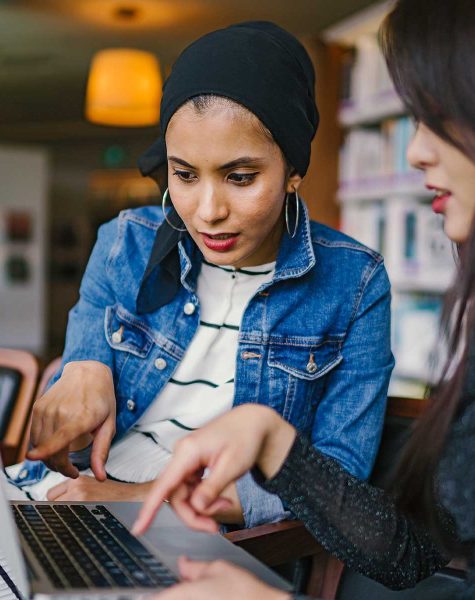 Two diverse women, one student and one teacher, working on the student's dissertation.