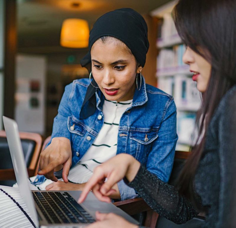 Two diverse women, one student and one teacher, working on the student's dissertation.